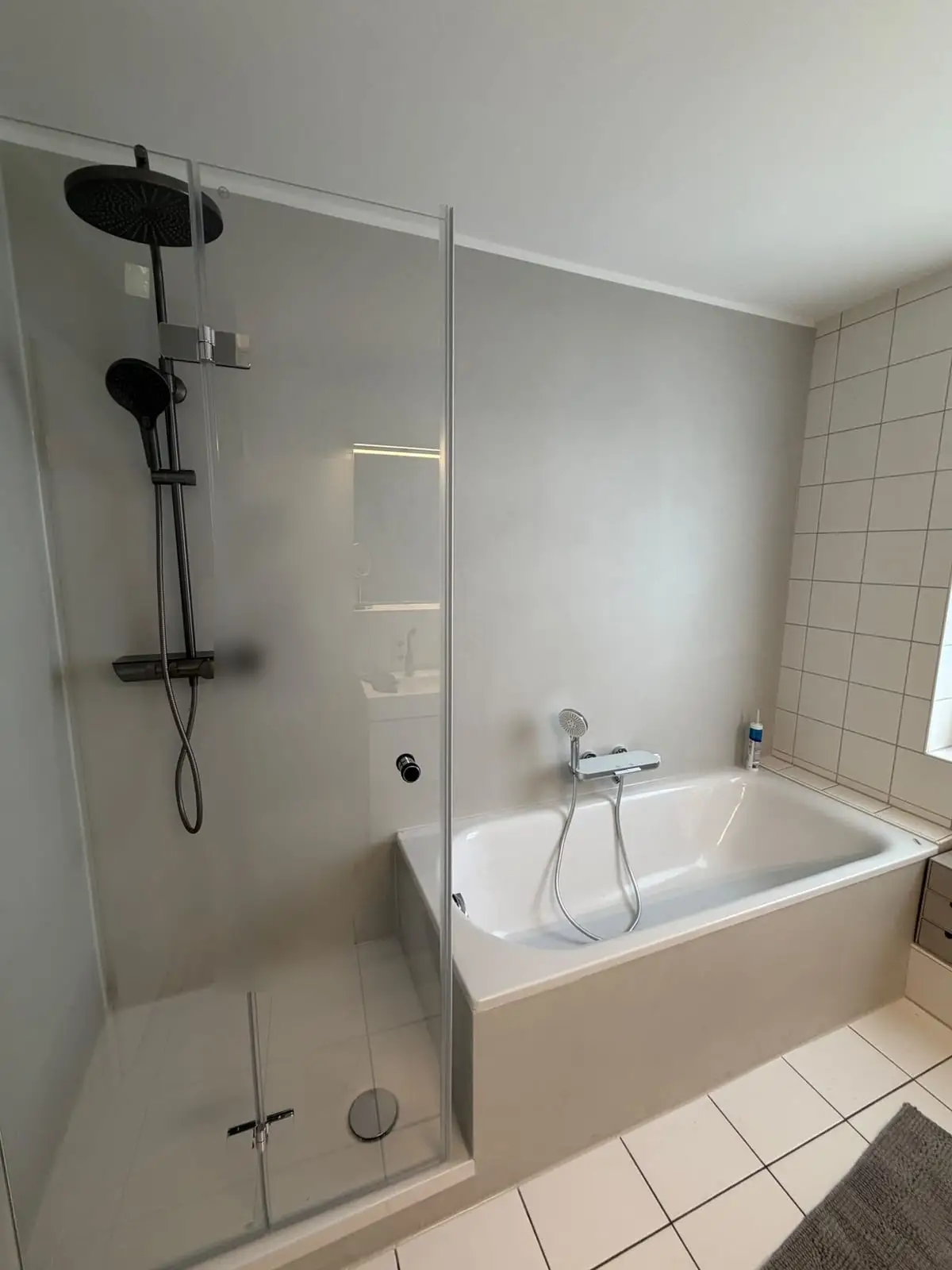 Das fertige Bad: fugenlose Wandflächen in Betonoptik an Dusche und Wanne, glatte weiße Decke