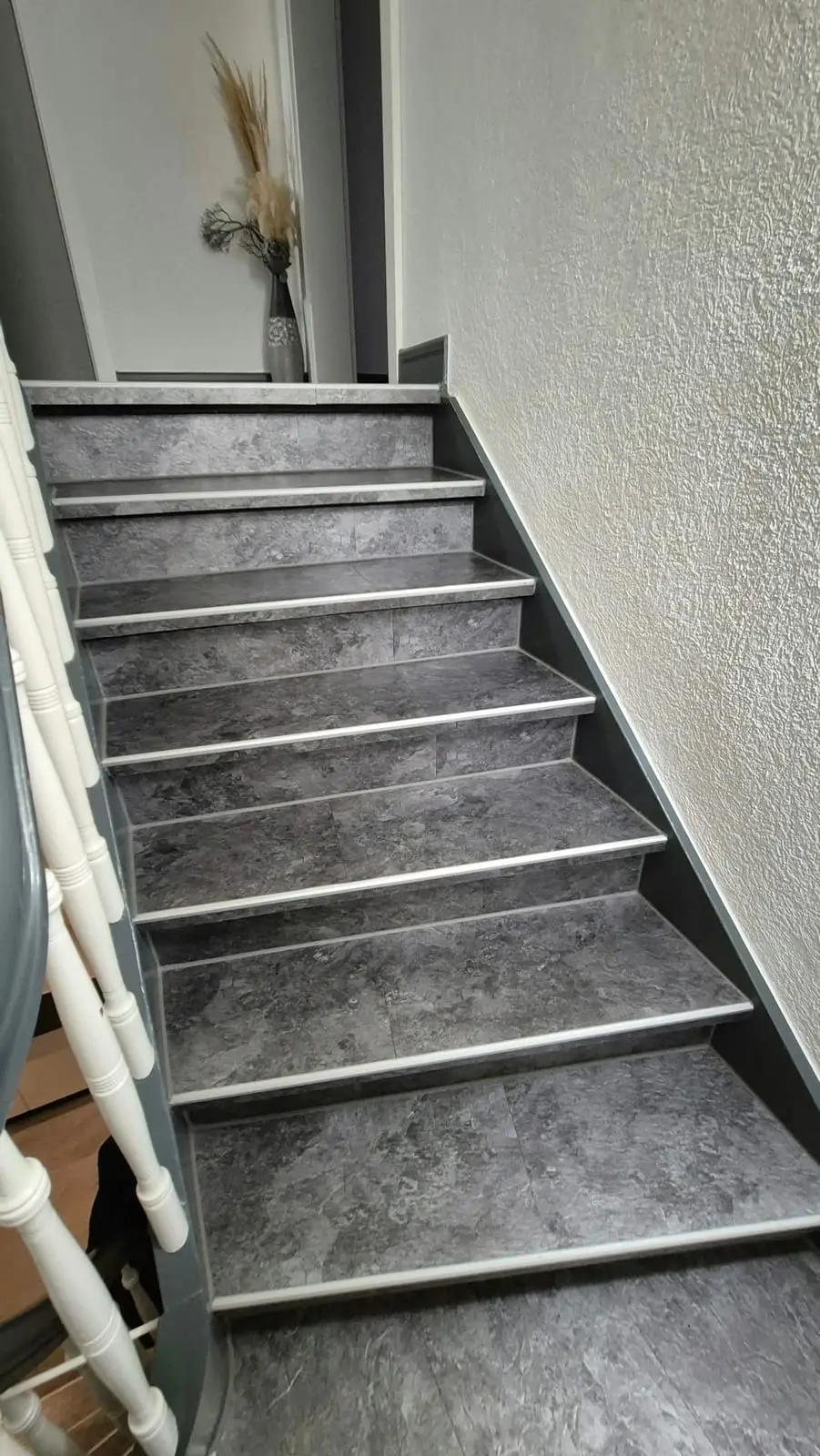 Treppe mit neuem Belag in Stein-Optik und weißen Geländerstäben