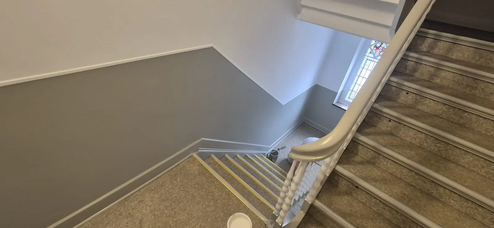 Altbau-Treppenhaus mit zweifarbiger Wand und weißem Geländer