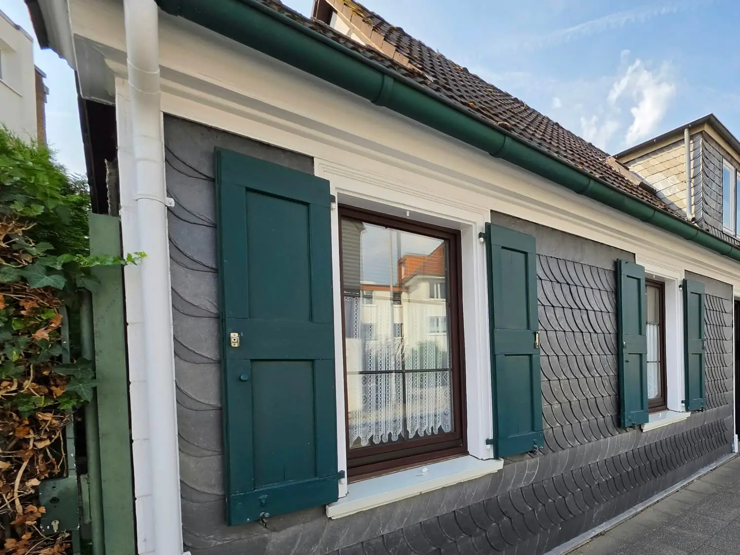 Bergisches Schieferhaus in Essen-Werden mit weißen Faschen und dunkelgrünen Klappläden